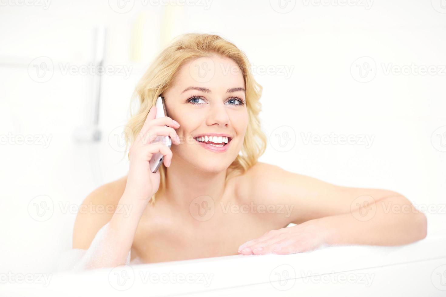 mulher falando ao telefone enquanto toma banho foto
