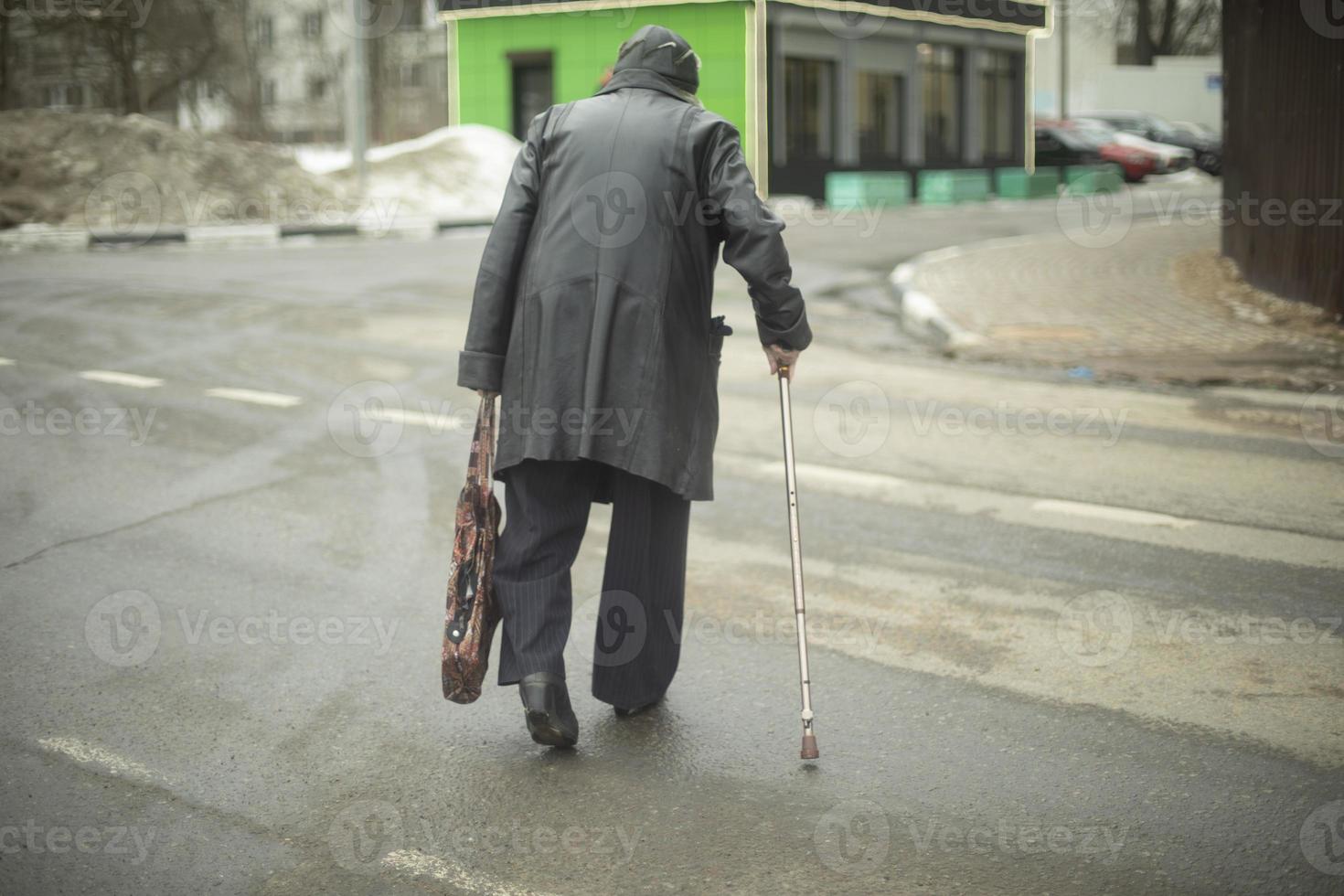 velha caminha pela estrada com jaqueta preta. pensionista na rússia na rua. foto