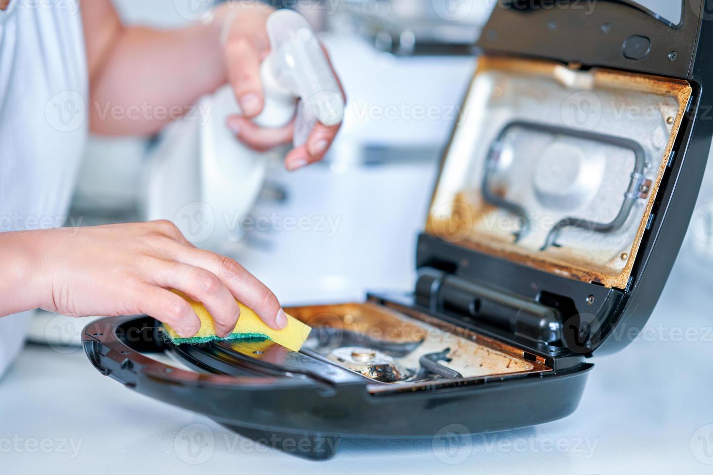 mulher limpando grelha ou torradeira na cozinha foto