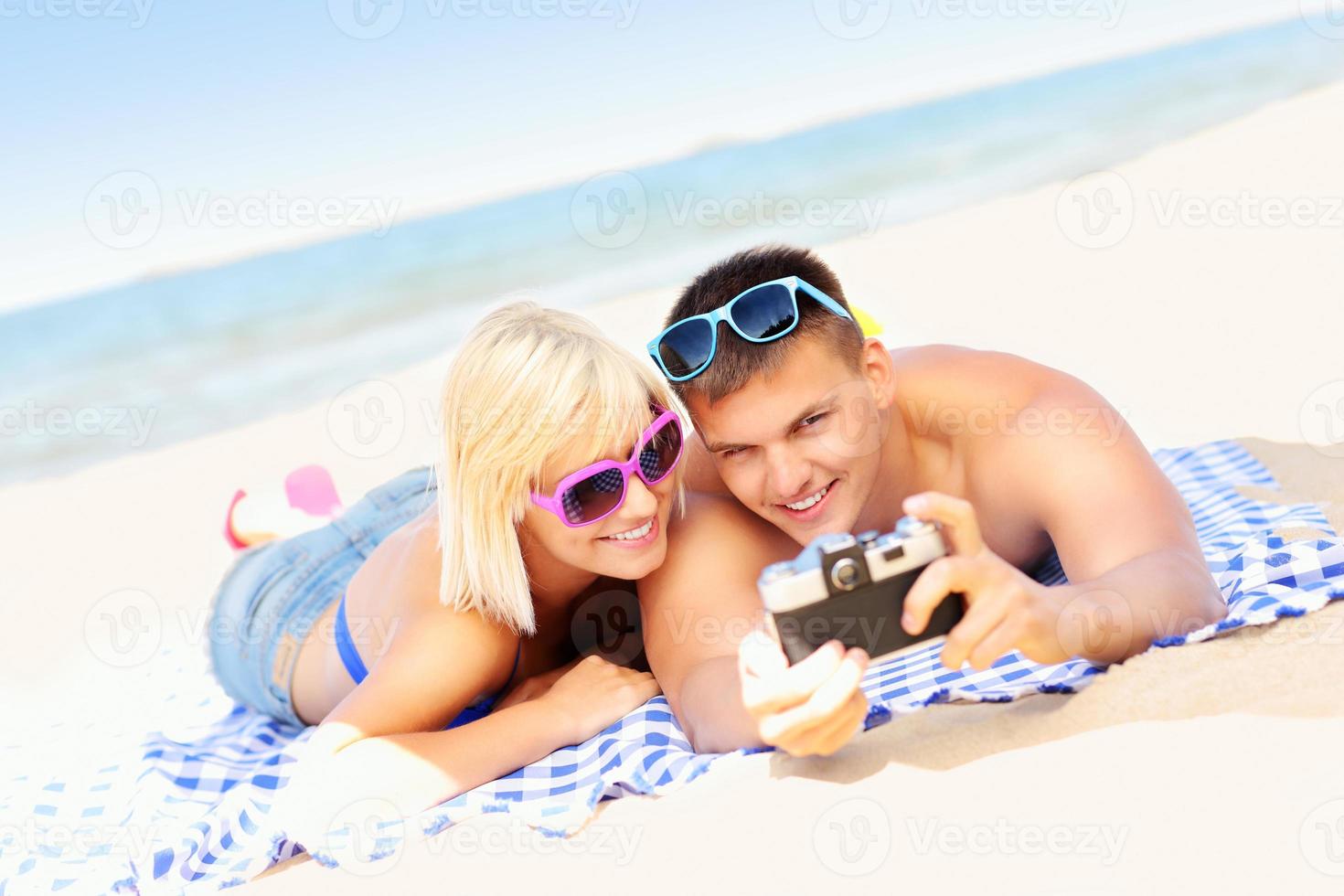 jovem casal tirando fotos na praia