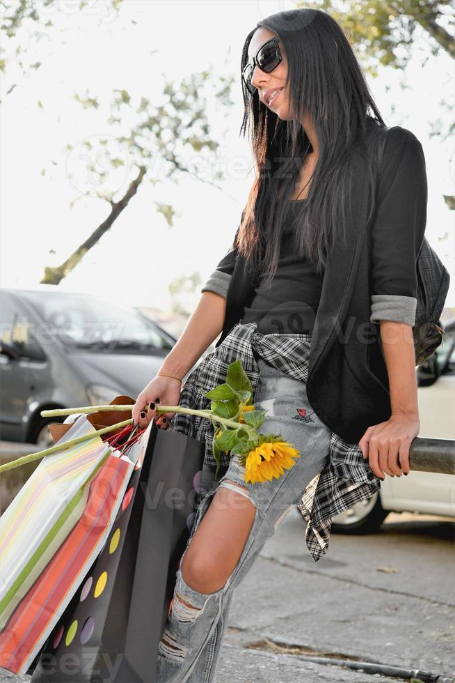 mulher bonita andando na rua com sacolas de compras. modelo feminino na moda na cidade com sacolas de compras. foto