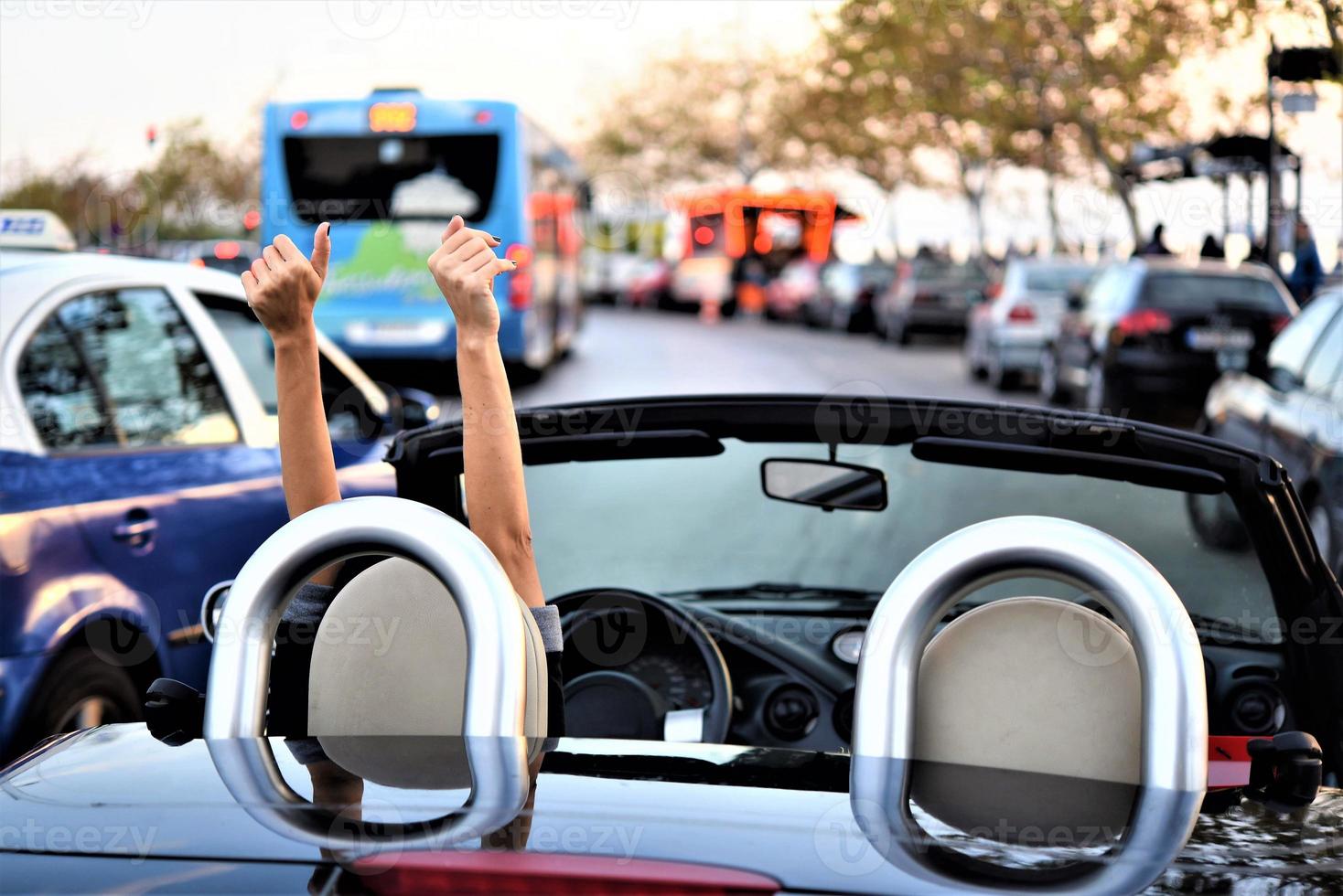 mulher bonita feliz dirigindo um carro esportivo conversível na cidade foto