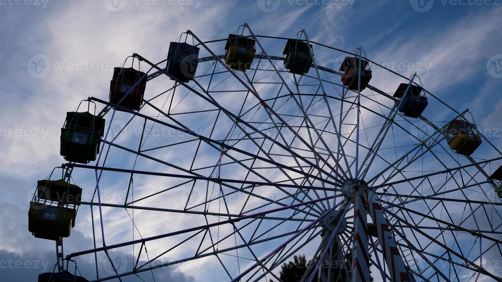 rodas gigantes coloridas no parque de diversões em um fundo de céu azul com nuvens. imagem tonificada. vista de baixo foto