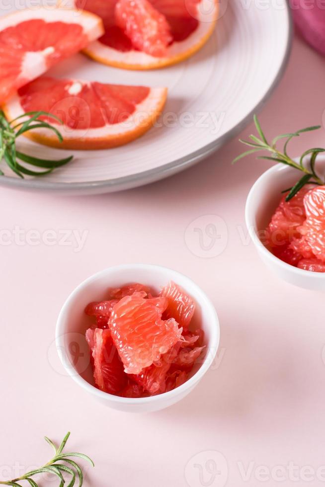 fatias de toranja suculenta e alecrim em uma tigela sobre a mesa. ingredientes do coquetel. visão vertical foto