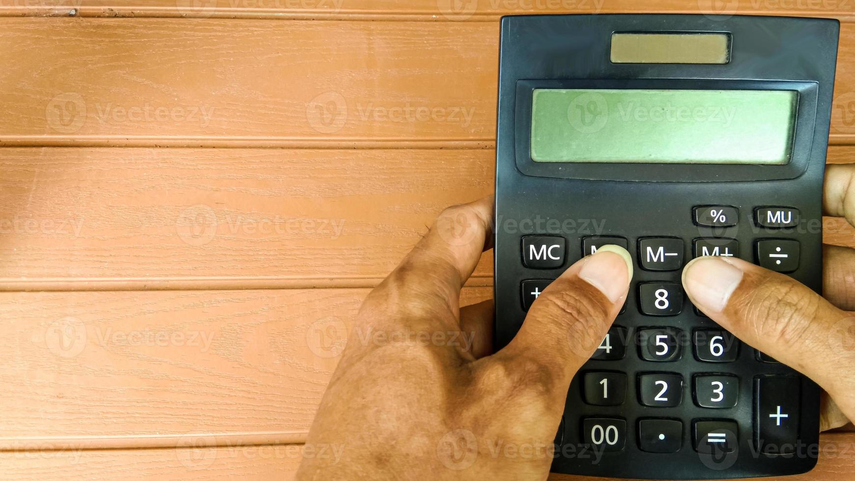mão de empresário trabalhando com calculadora na mesa de madeira foto