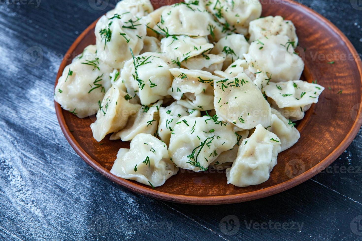 pelmeni russo tradicional ou ravioli, bolinhos com carne em fundo preto de madeira. comida russa e conceito de cozinha russa. foto