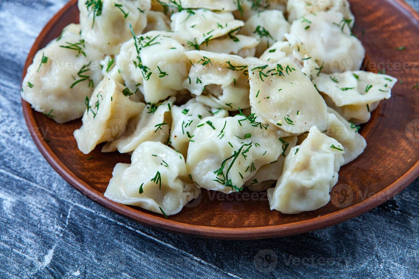 pelmeni russo tradicional ou ravioli, bolinhos com carne em fundo preto de madeira. comida russa e conceito de cozinha russa. foto