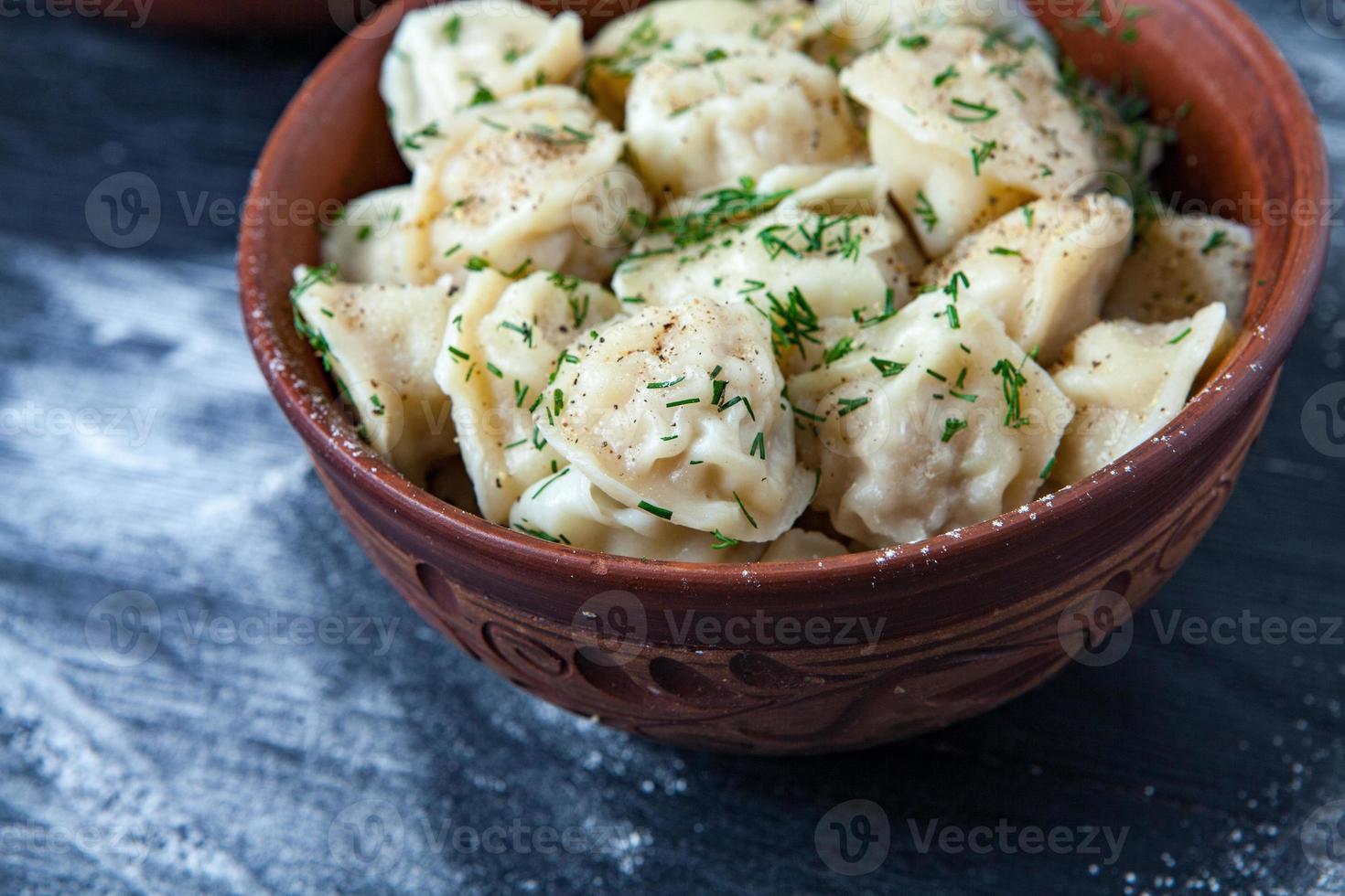 pelmeni russo tradicional ou ravioli, bolinhos com carne em fundo preto de madeira. comida russa e conceito de cozinha russa. foto