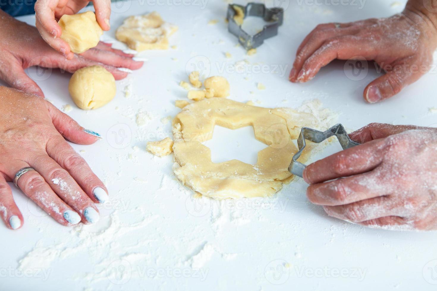 família cozinhando bolos caseiros. mãos de mães e filhos segurando cortadores de biscoito. configuração plana de cozinha familiar. doce lar. conceito de felicidade. foto