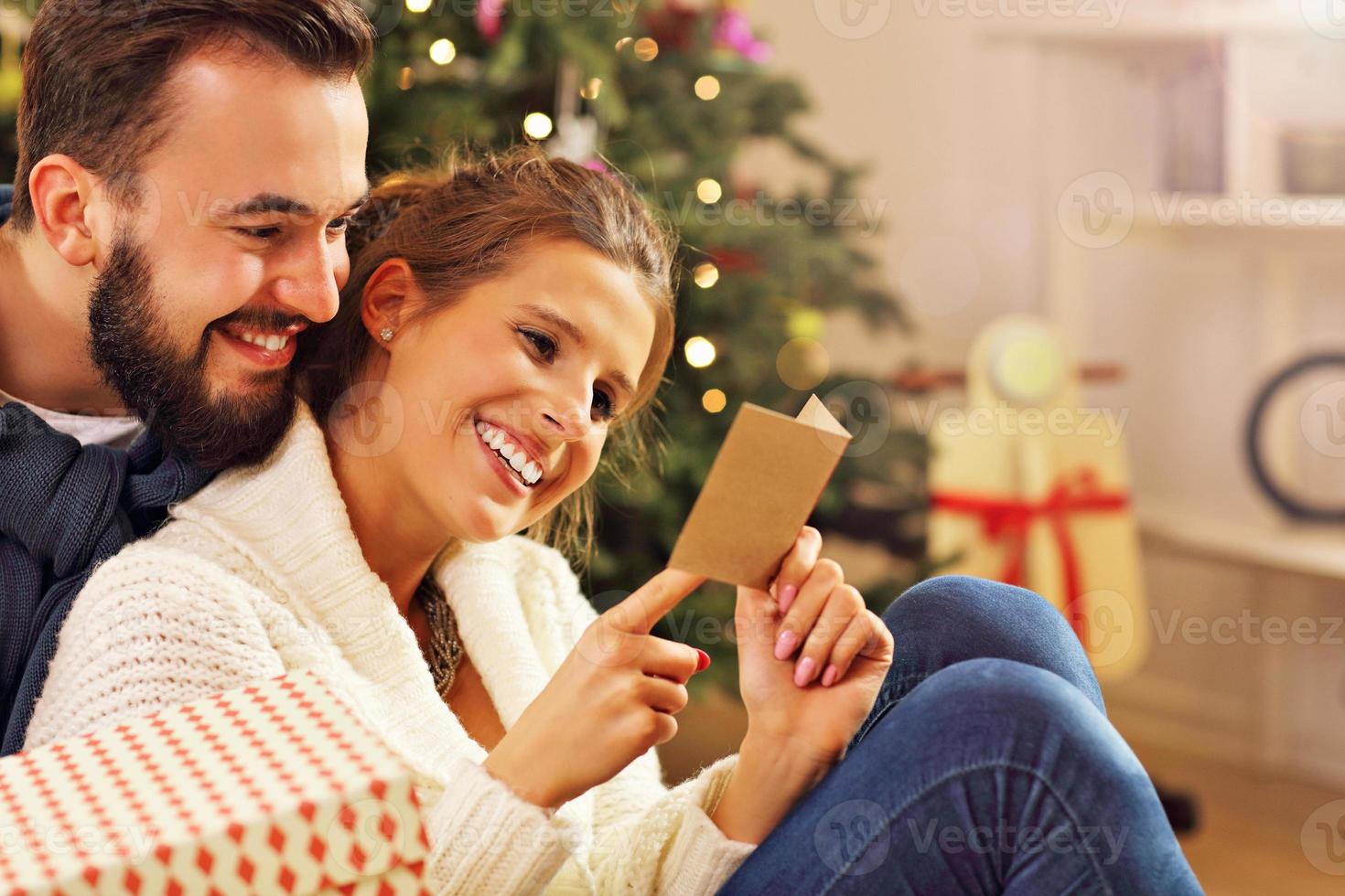 jovem casal com presente sobre a árvore de natal foto