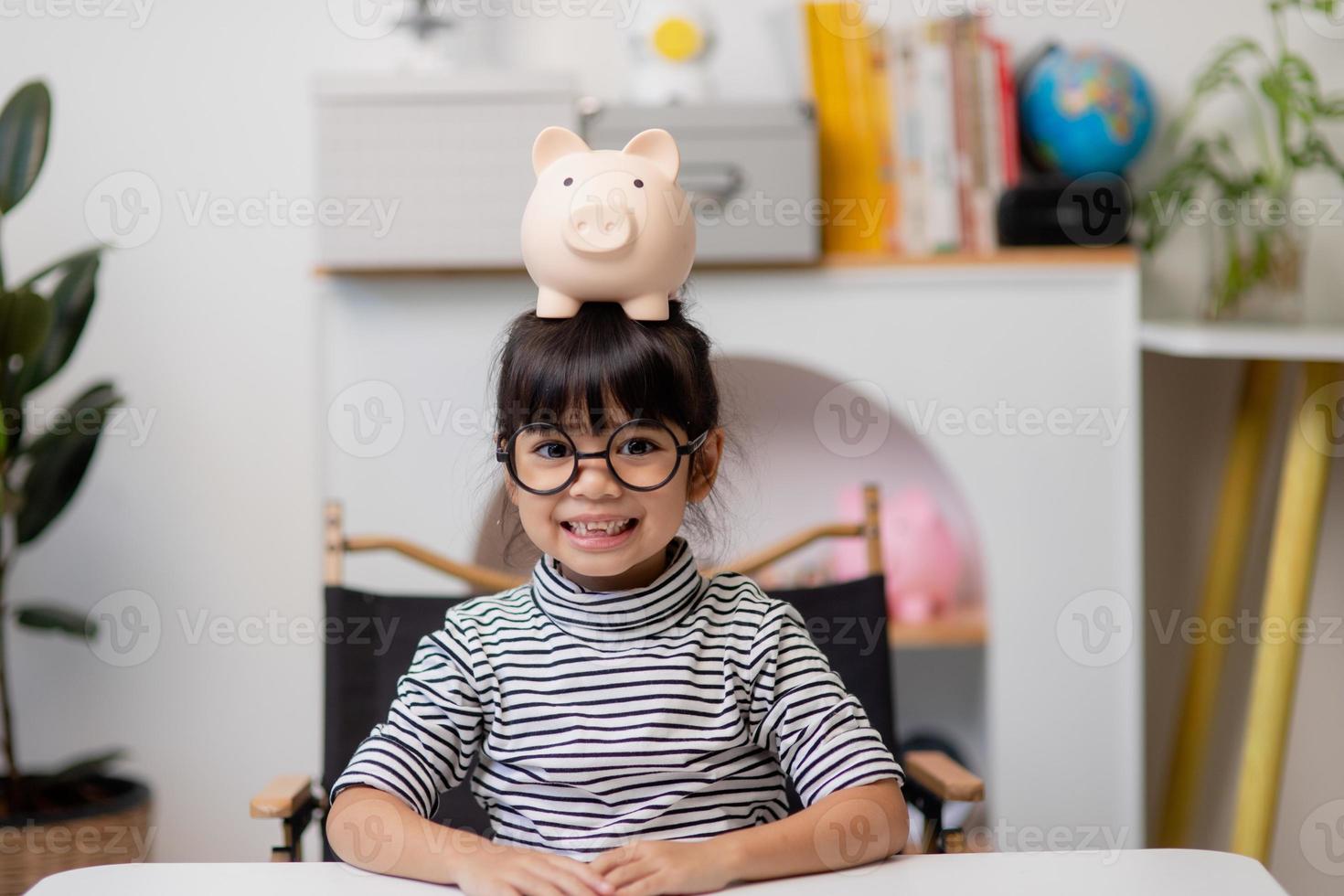 menina asiática economizando dinheiro em um cofrinho, aprendendo sobre economia, criança economizando dinheiro para educação futura. conceito de dinheiro, finanças, seguro e pessoas foto