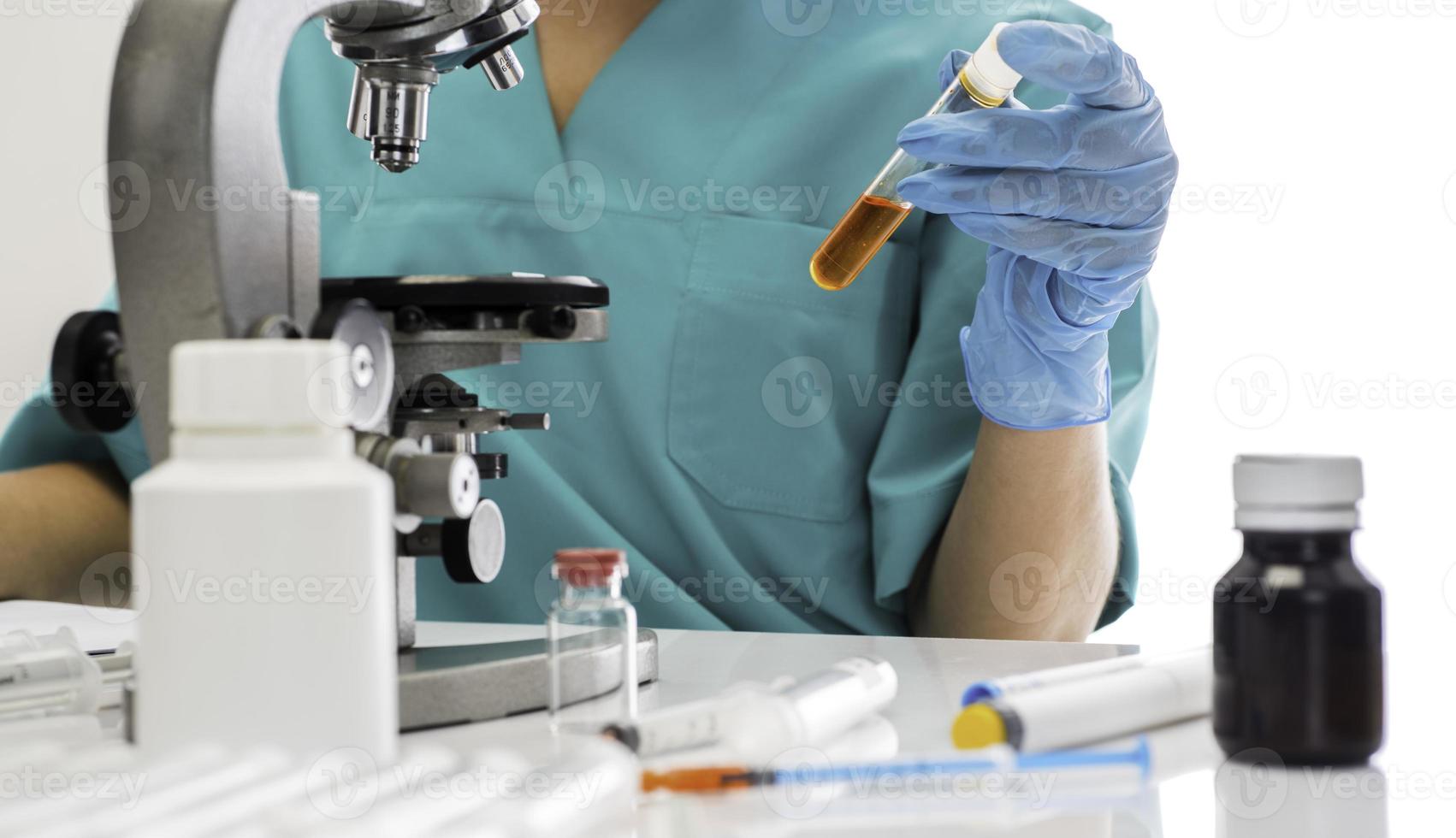 cientista em luvas médicas azuis e uniforme aprendendo amostras covid-19 com microscópio em laboratório. foto