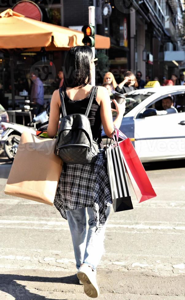 mulher bonita andando na rua com sacolas de compras. modelo feminino na moda na cidade segurando sacolas de compras. foto