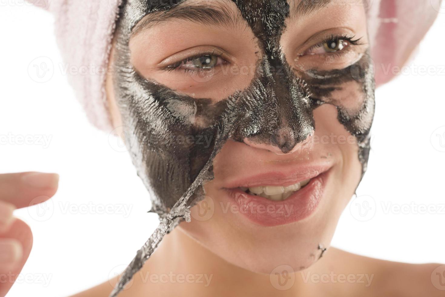 máscara facial preta. linda garota acumulando máscara preta. conceito de beleza foto
