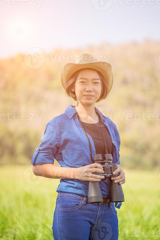 mulher usa chapéu e segura binóculo no campo de grama foto