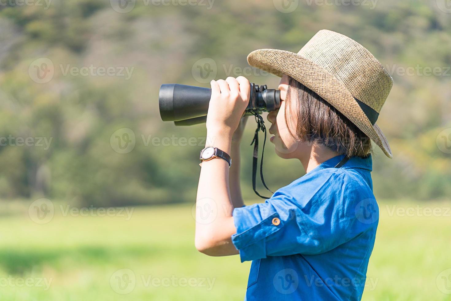 mulher usa chapéu e segura binóculo no campo de grama foto