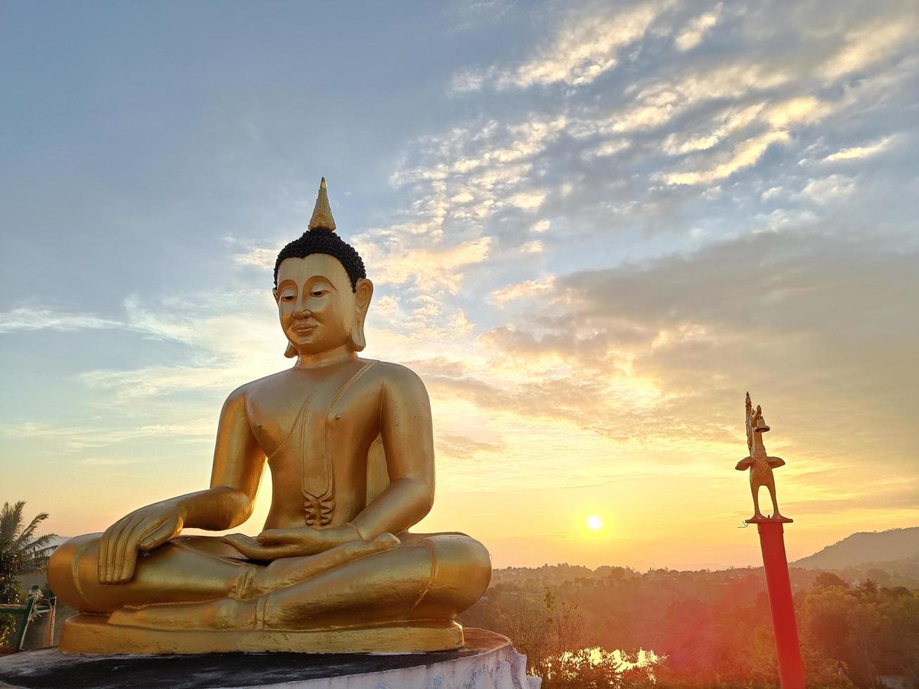 bela estátua dourada de buda contra o céu pôr do sol no templo da tailândia foto