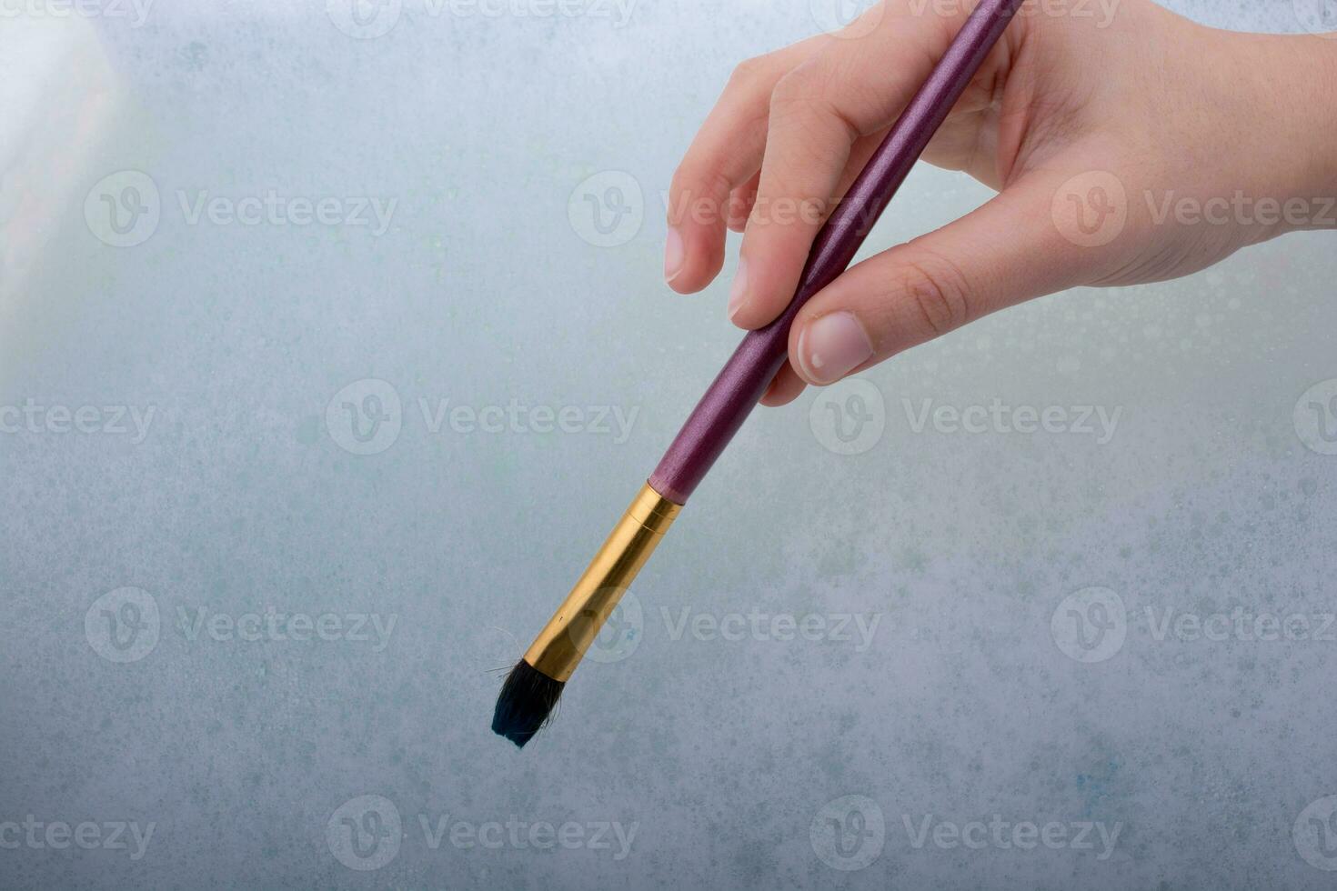 mão segurando um pincel na água com espuma foto