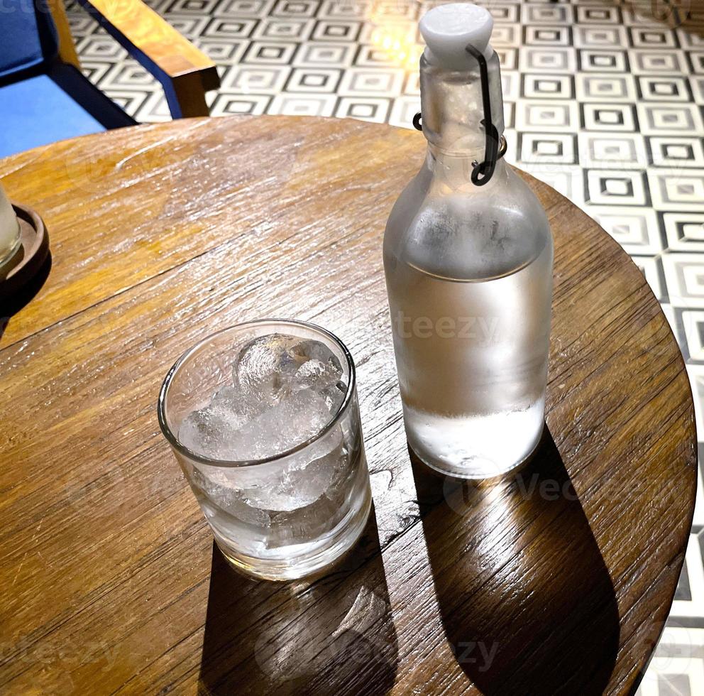 refrescante vodka gelada na garrafa com pedras de gelo no copo servido no pub foto