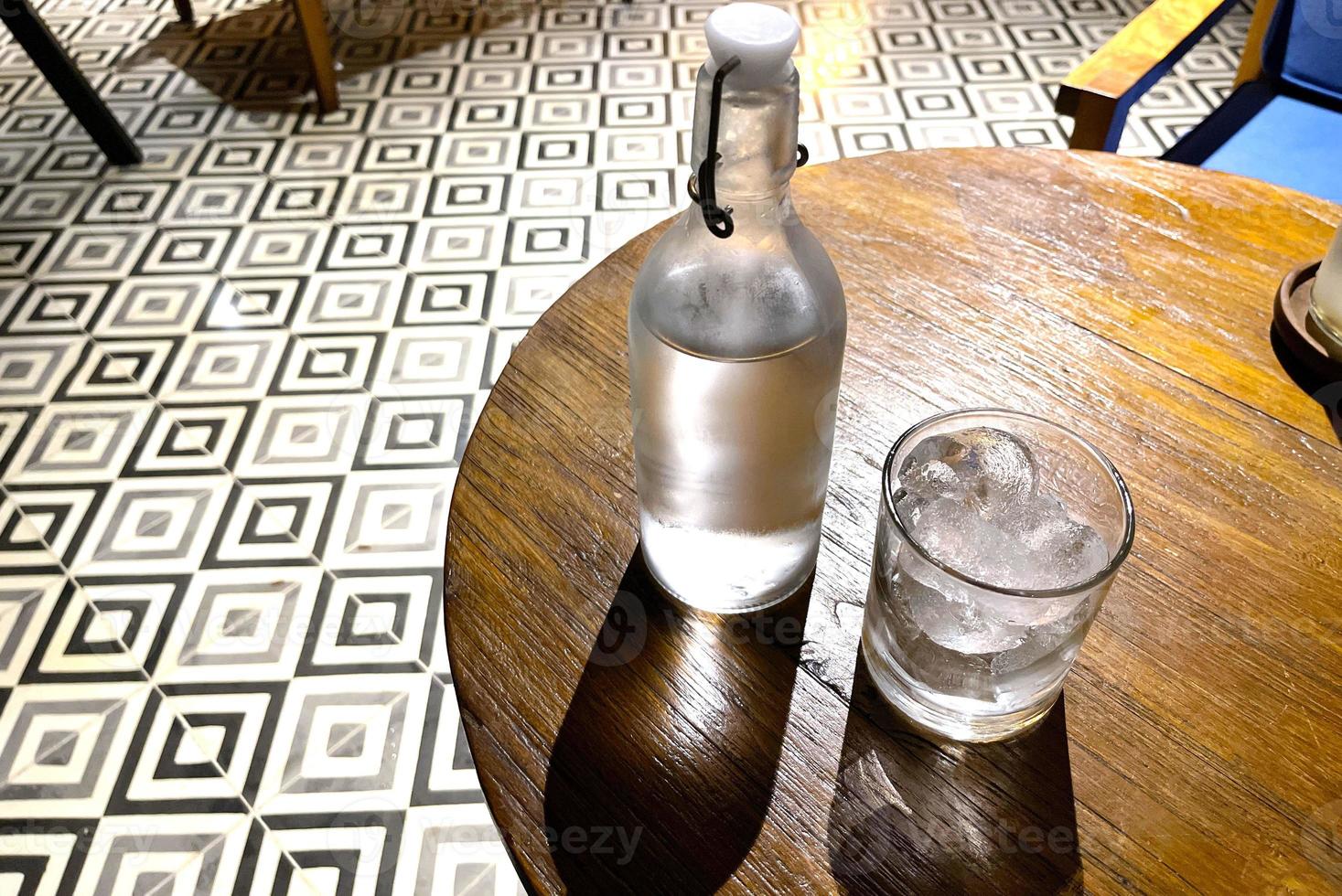 refrescante vodka gelada na garrafa com pedras de gelo no copo servido no pub foto