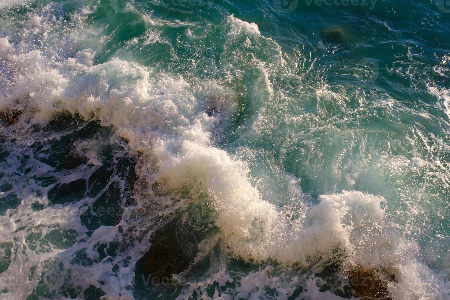 rocha quebrando com água do mar, ao ar livre, ondas e rochas, respingos e espuma, vista superior. foto