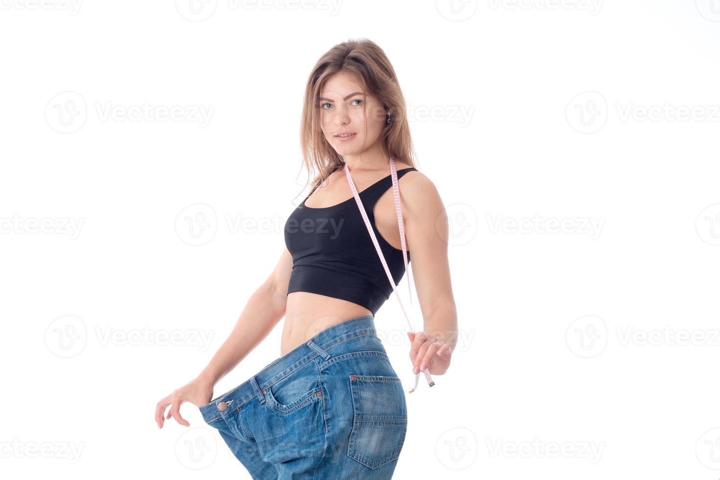menina esbelta mantém a roleta e fica em um grande fundo branco isolado de calças jeans foto