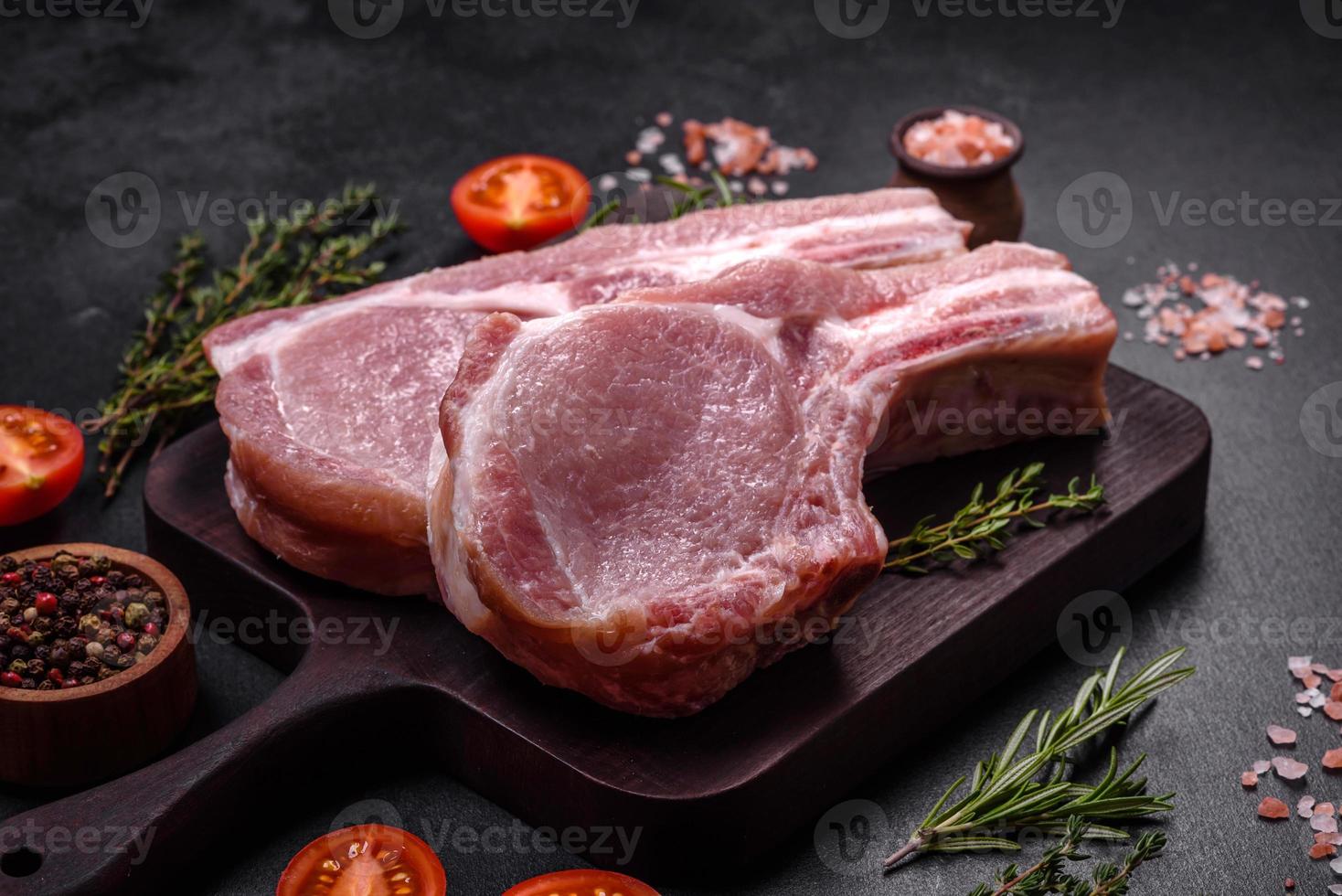 carne de porco crua fresca nas costelas com especiarias e ervas em uma tábua de madeira foto