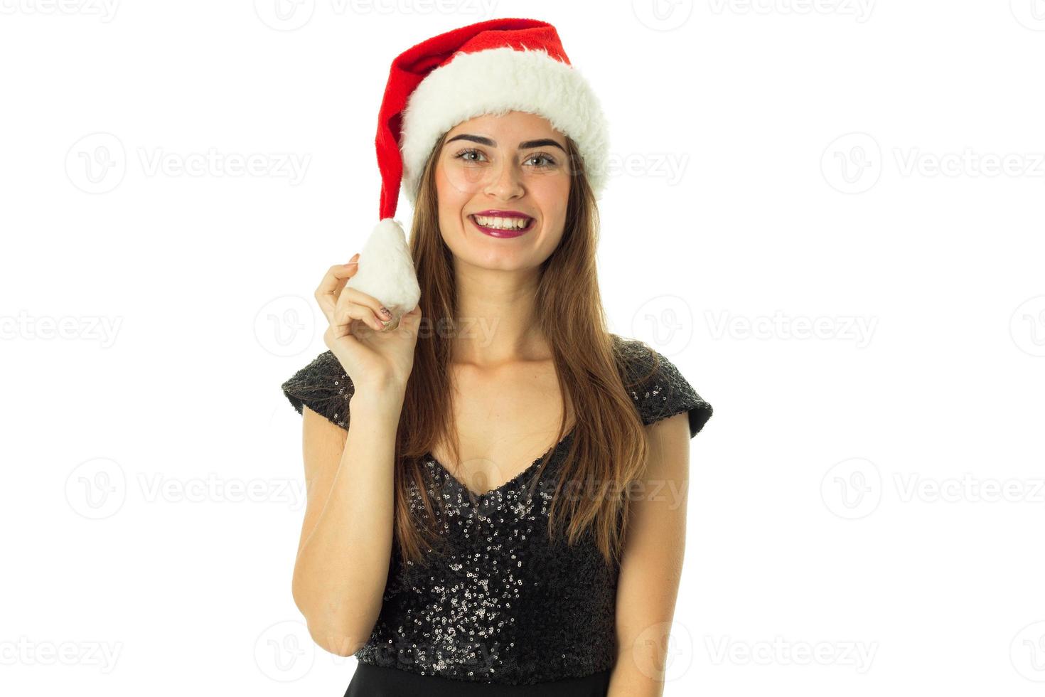 menina de chapéu de Papai Noel olhando e sorrindo para a câmera foto