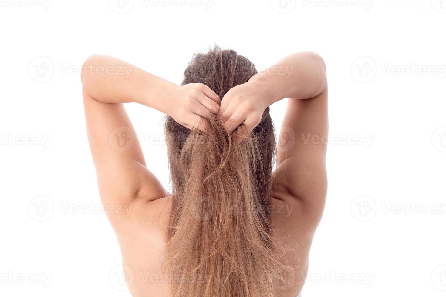 a garota fica de frente para trás e mantém o cabelo das mãos isolado no fundo branco foto