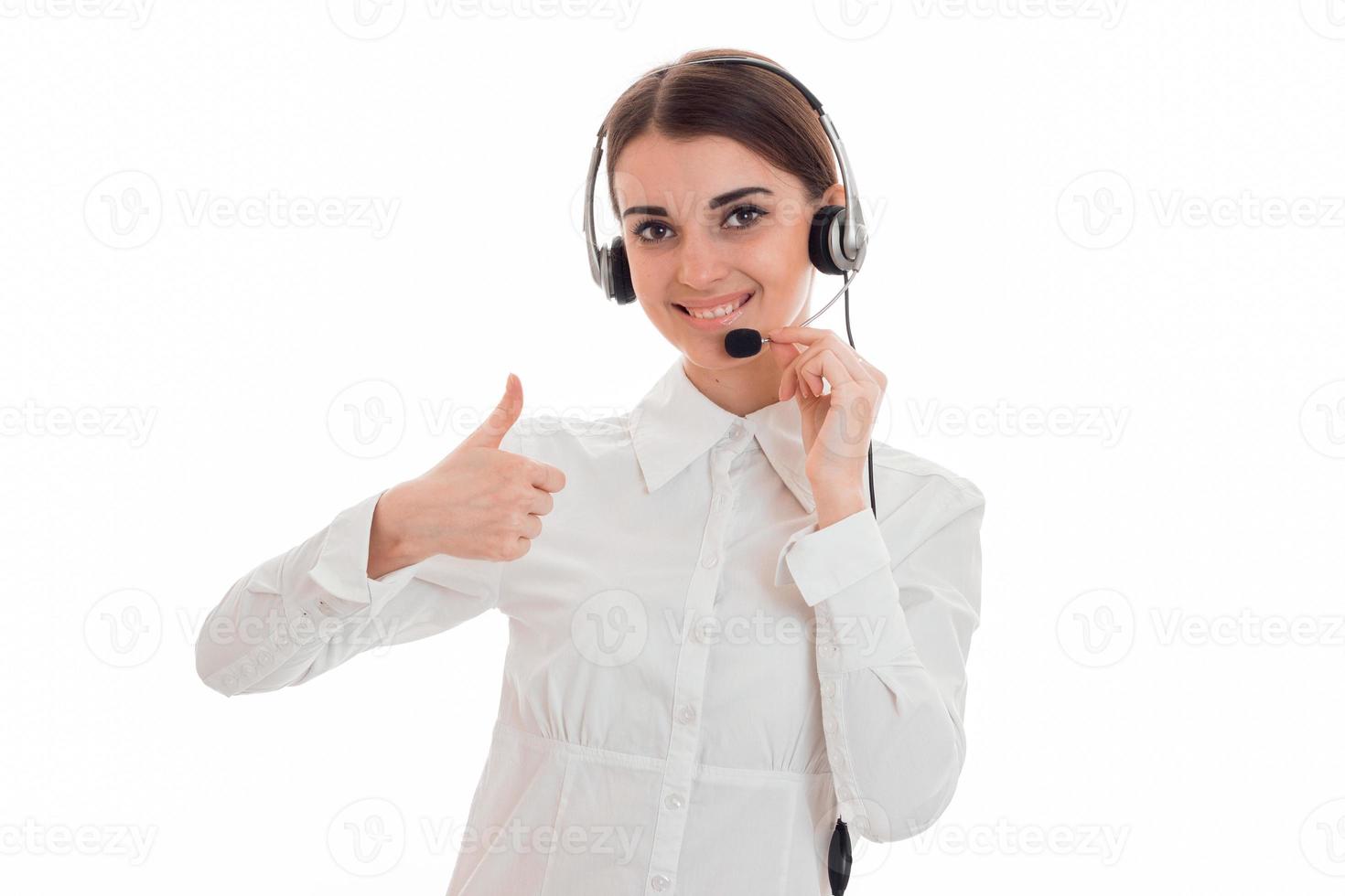 linda jovem em fones de ouvido e sorrindo em uma camisa branca e mostra a classe foto