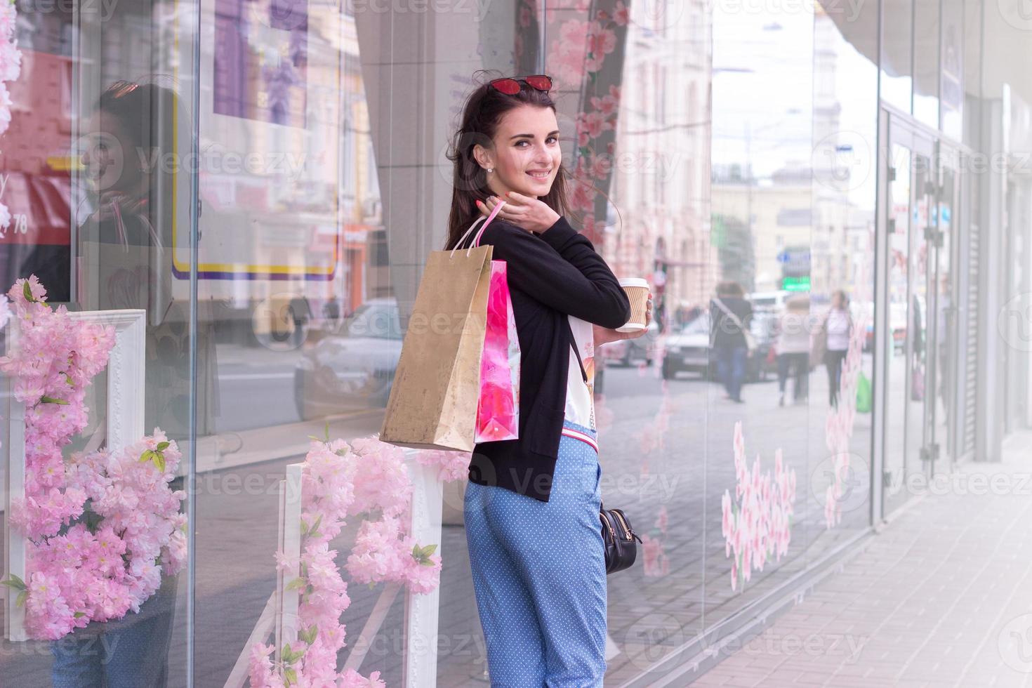 encantadora garota feliz está de pé na rua com compras foto
