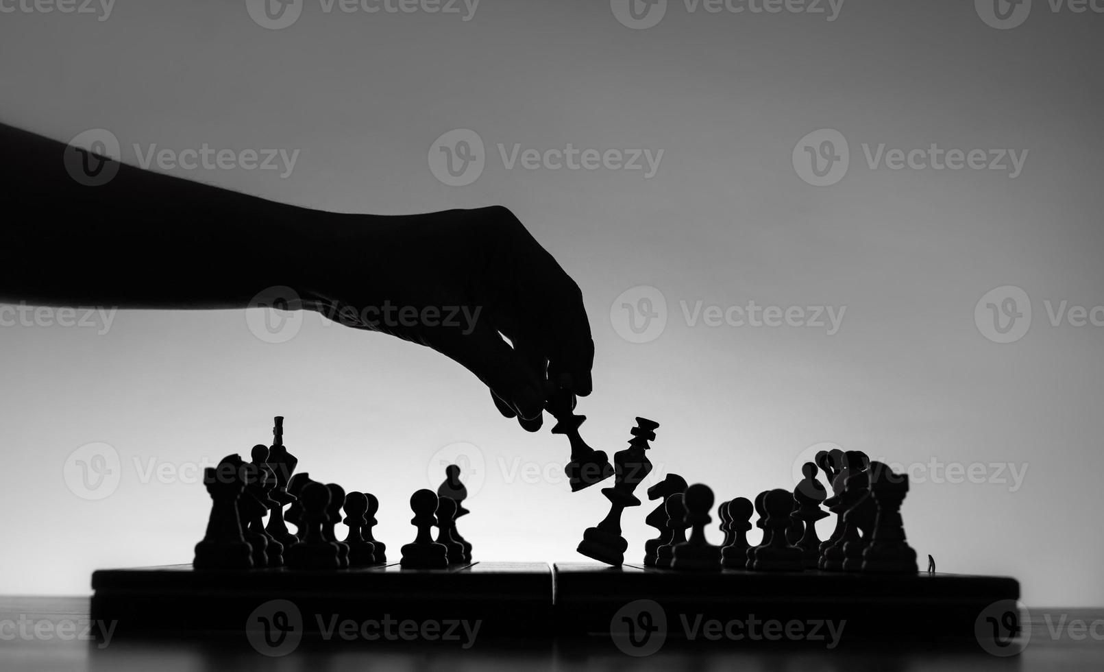 tabuleiro de xadrez com silhuettes de peças de xadrez em fundo branco. conceito de ideias de negócios e ideias de competição e estratégia. foto de arte clássica preto e branco. rei foi derrotado pela rainha. xeque-mate.