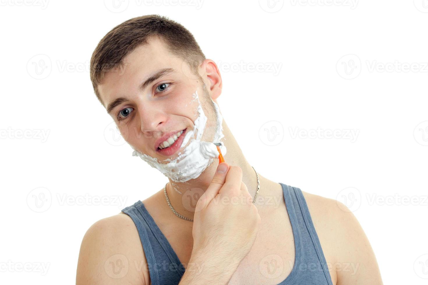 retrato aproximado de um jovem bonitinho com espuma no rosto que raspa a barba e sorri foto