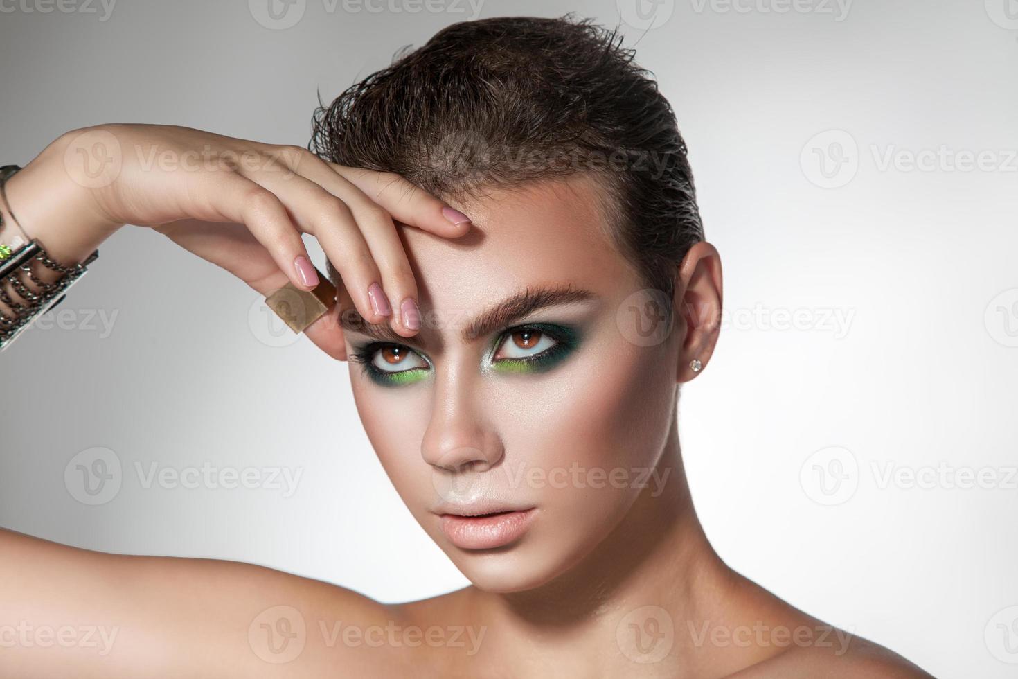 retrato horizontal da jovem beleza com maquiagem de cores verdes e penteado curto foto