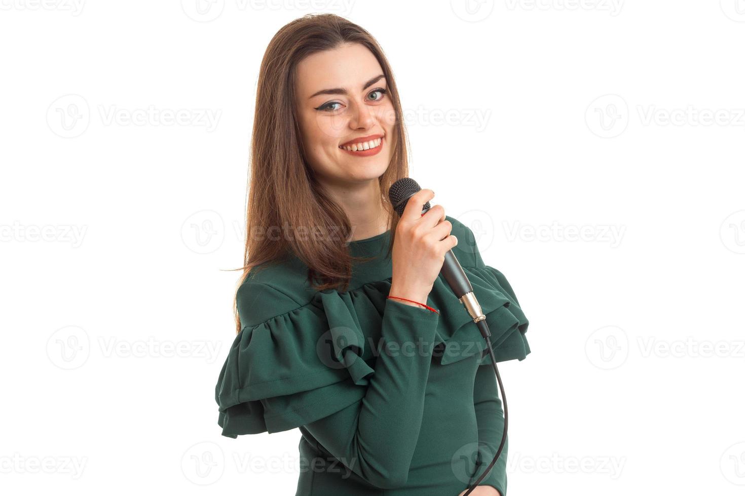 jovem alegre em vestido verde cantando música com karaokê foto