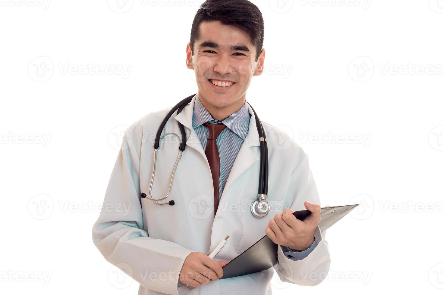 bonito bonito morena médico de uniforme com estetoscópio no pescoço posando e sorrindo na câmera isolada no fundo branco foto