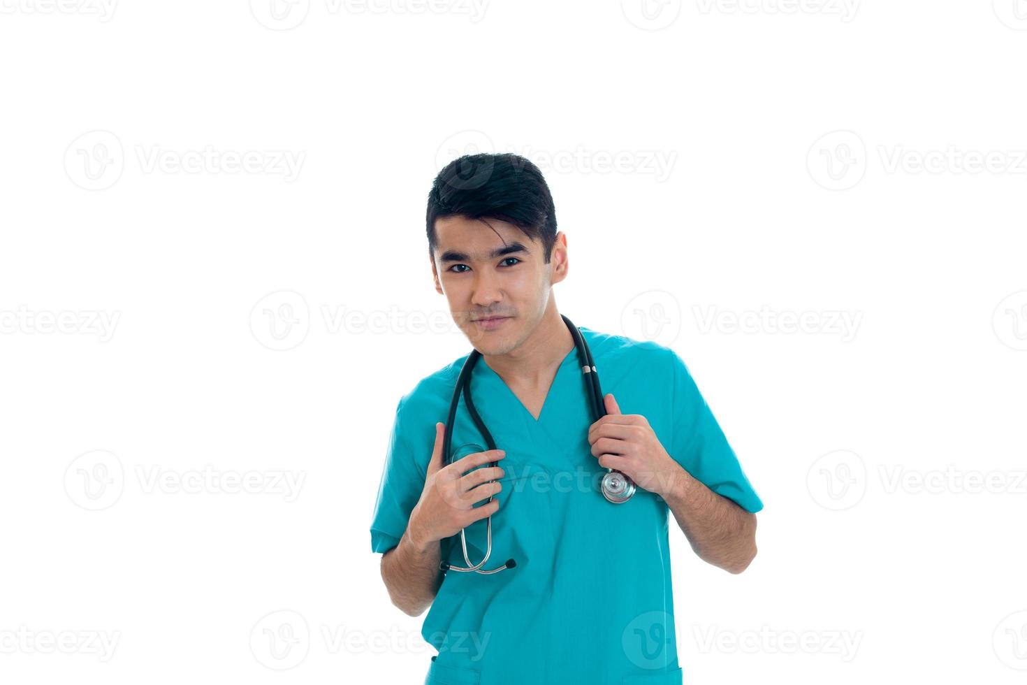 bonito jovem médico masculino com estetoscópio em uniforme posando isolado no fundo branco foto