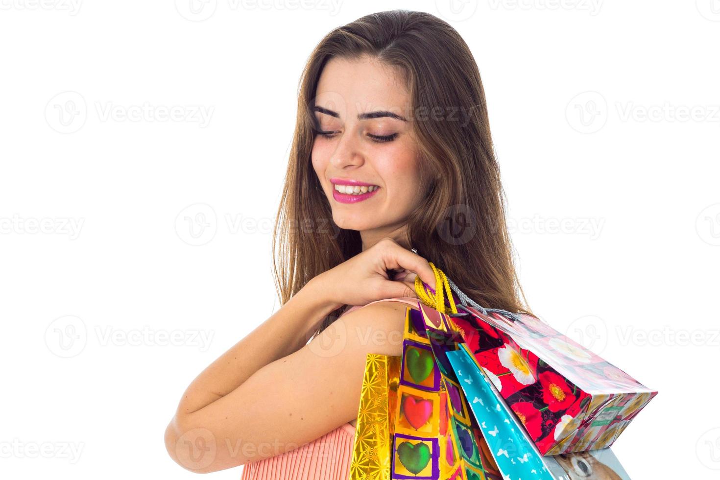 menina sorrindo olhando para baixo e mantém o close-up de pacotes brilhantes do ombro foto