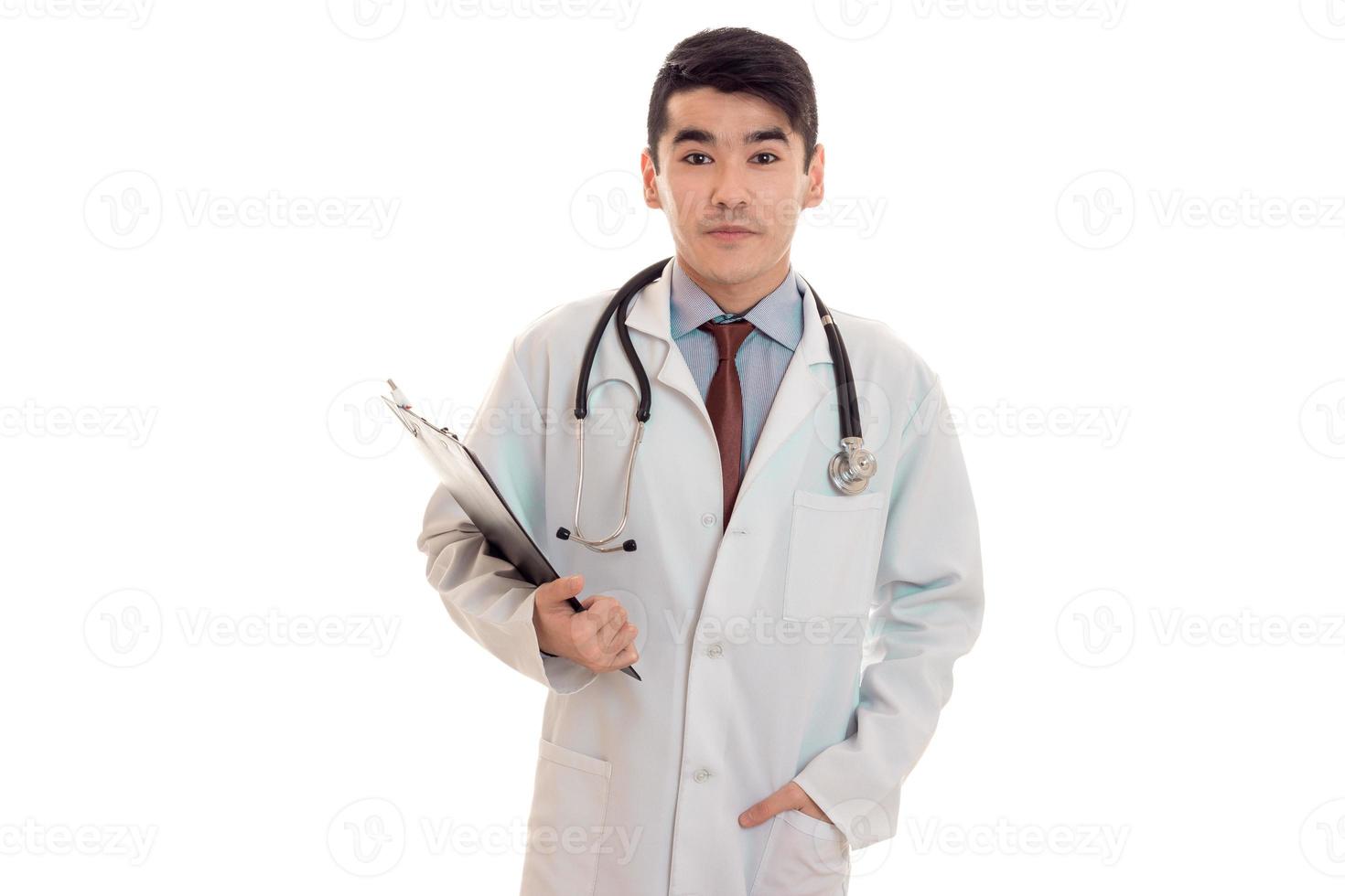 um jovem médico em um jaleco branco com um estetoscópio segurando um tablet para valores mobiliários foto