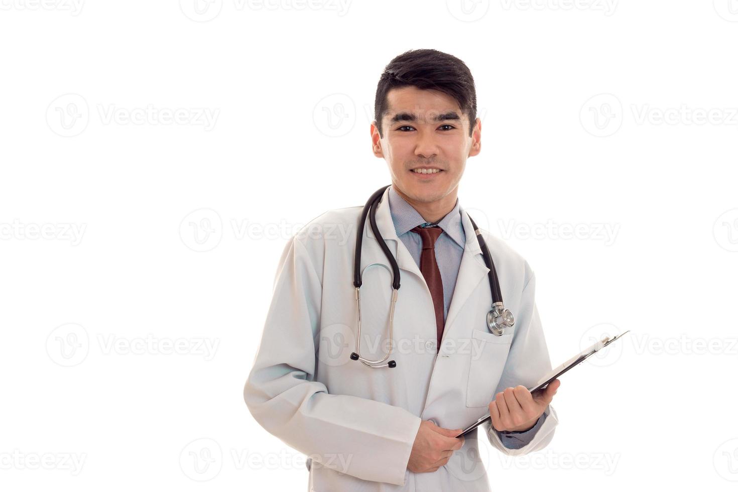 jovem médico lindo de uniforme azul com estetoscópio no pescoço sorrindo para a câmera isolada no fundo branco foto