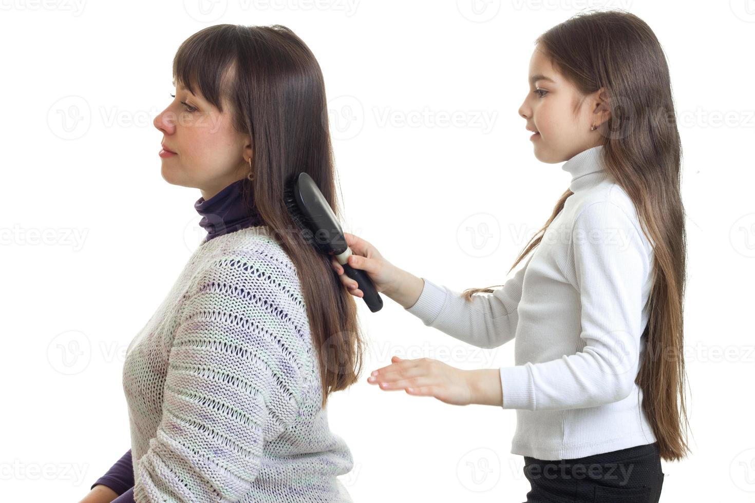menina penteando o cabelo para sua mãe foto