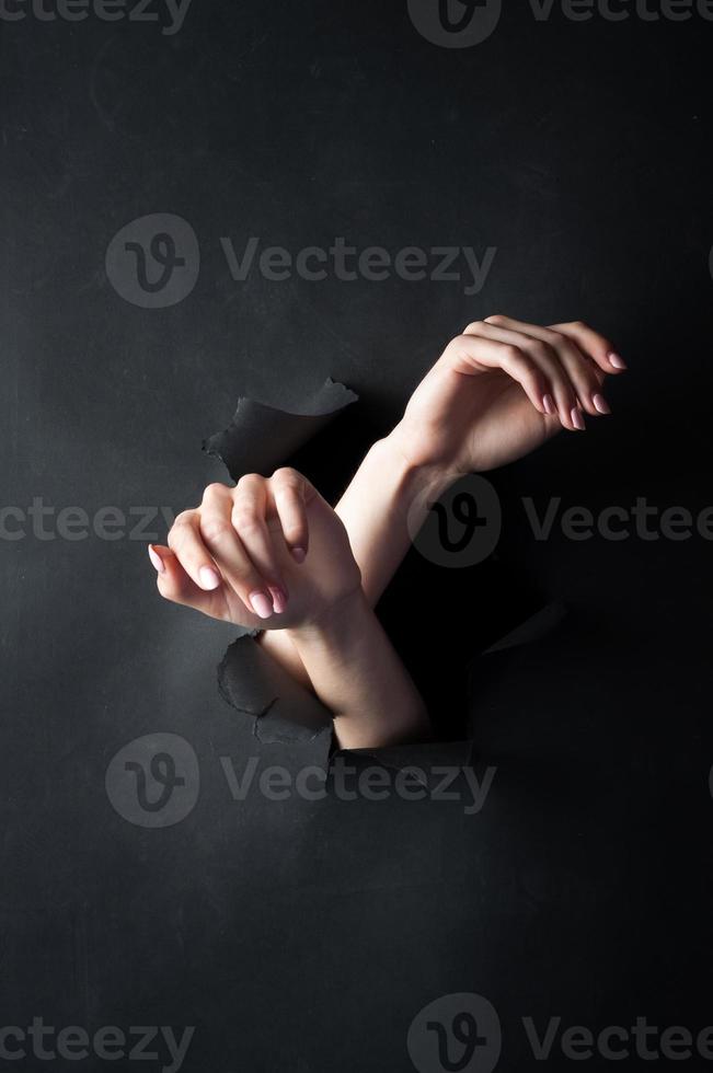 mãos femininas, em um fundo preto e rasgado. foto