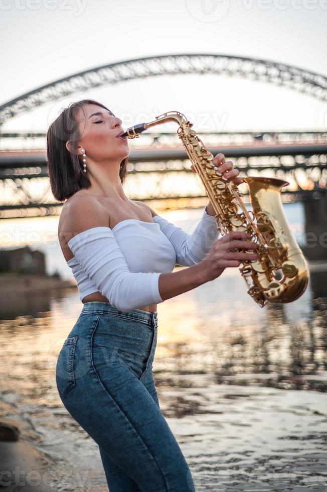 mulher tocando saxofone ao pôr do sol foto