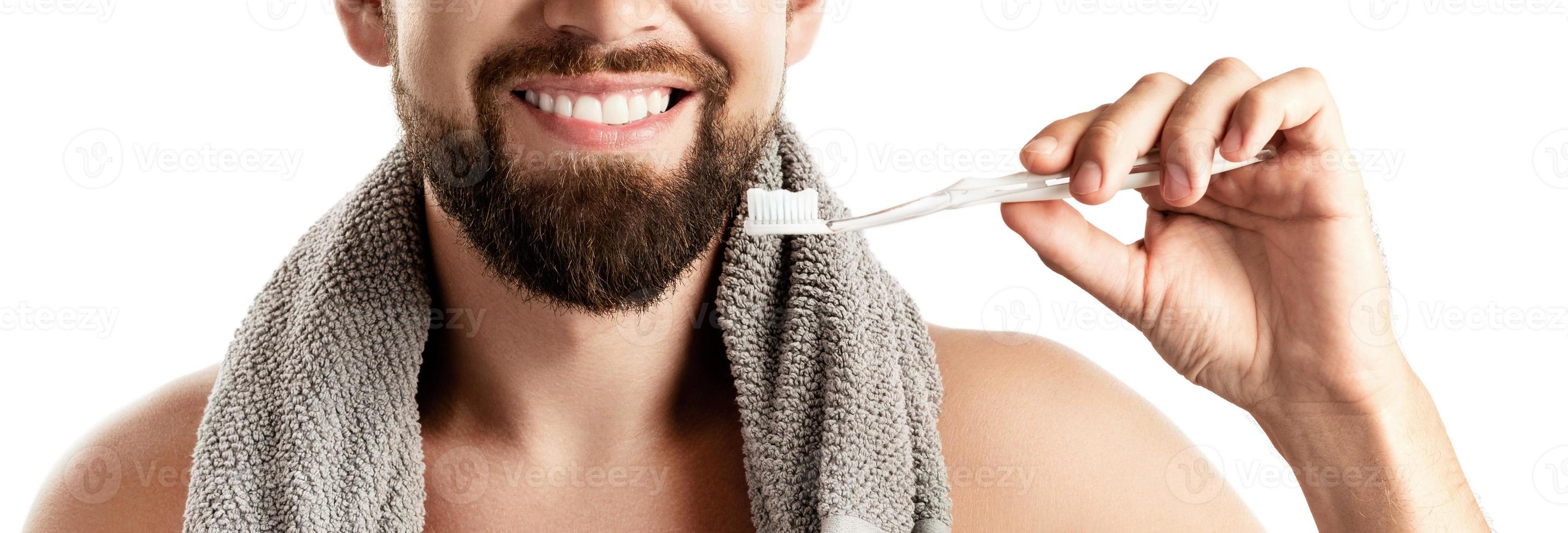 homem bonito com lindo sorriso segurando a escova de dentes no fundo branco foto