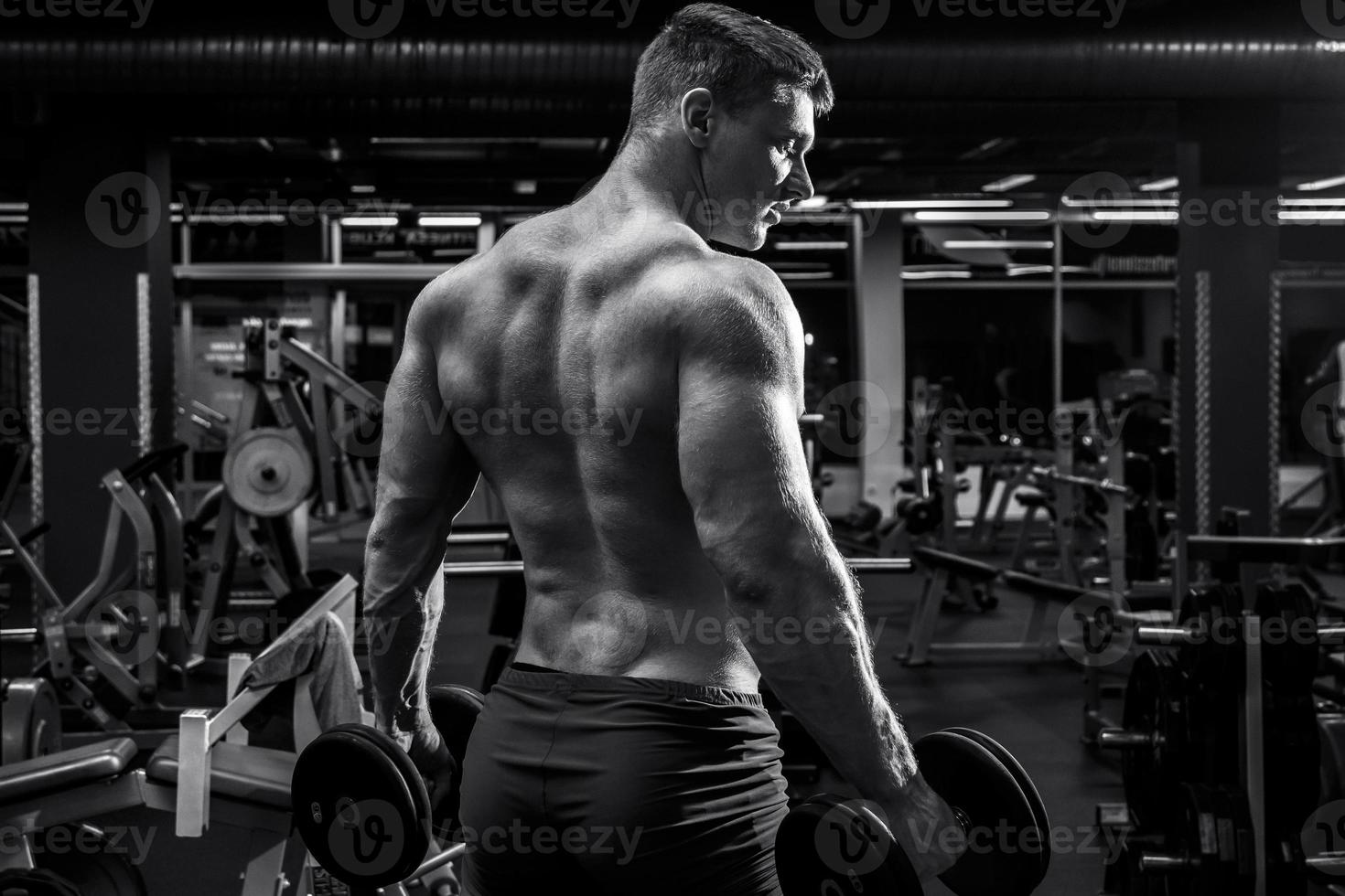 homem musculoso com halteres no ginásio foto