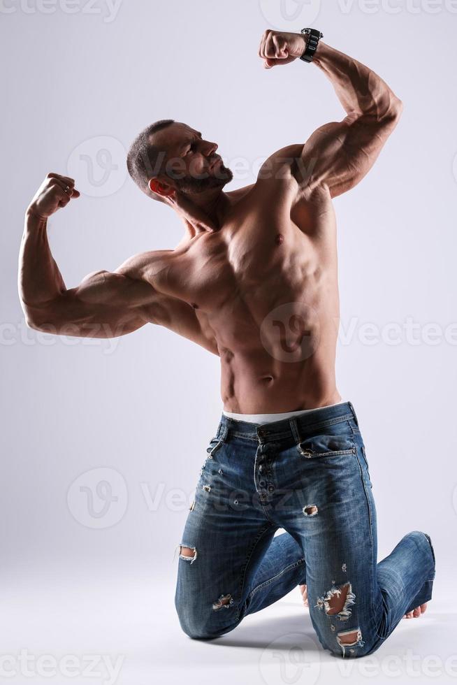 bonito homem musculoso vestindo jeans posando no estúdio foto