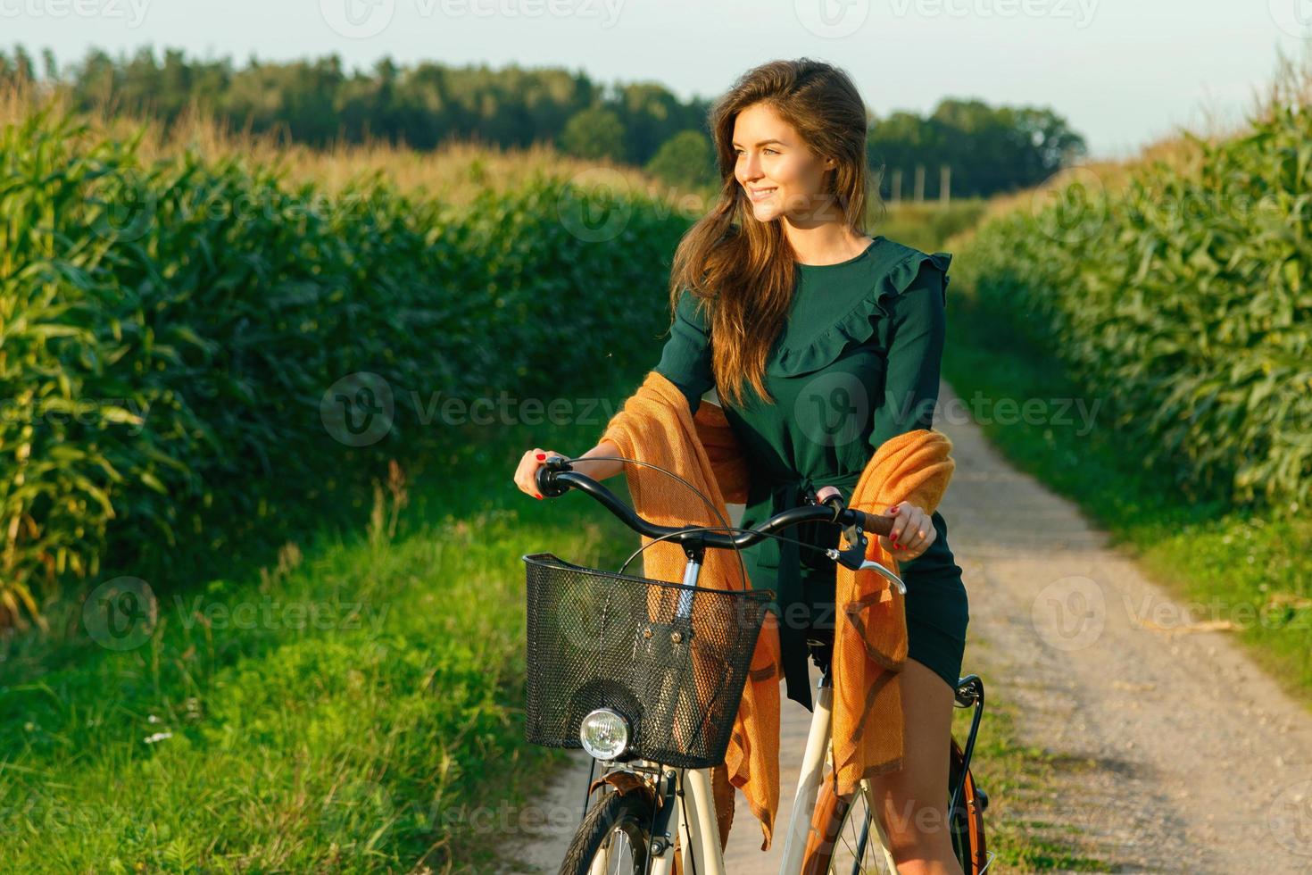 a mulher está pedalando pela estrada secundária no milharal foto