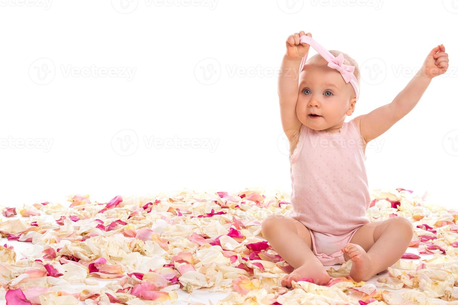 menina bonita sentada rodeada de pétalas de rosa foto