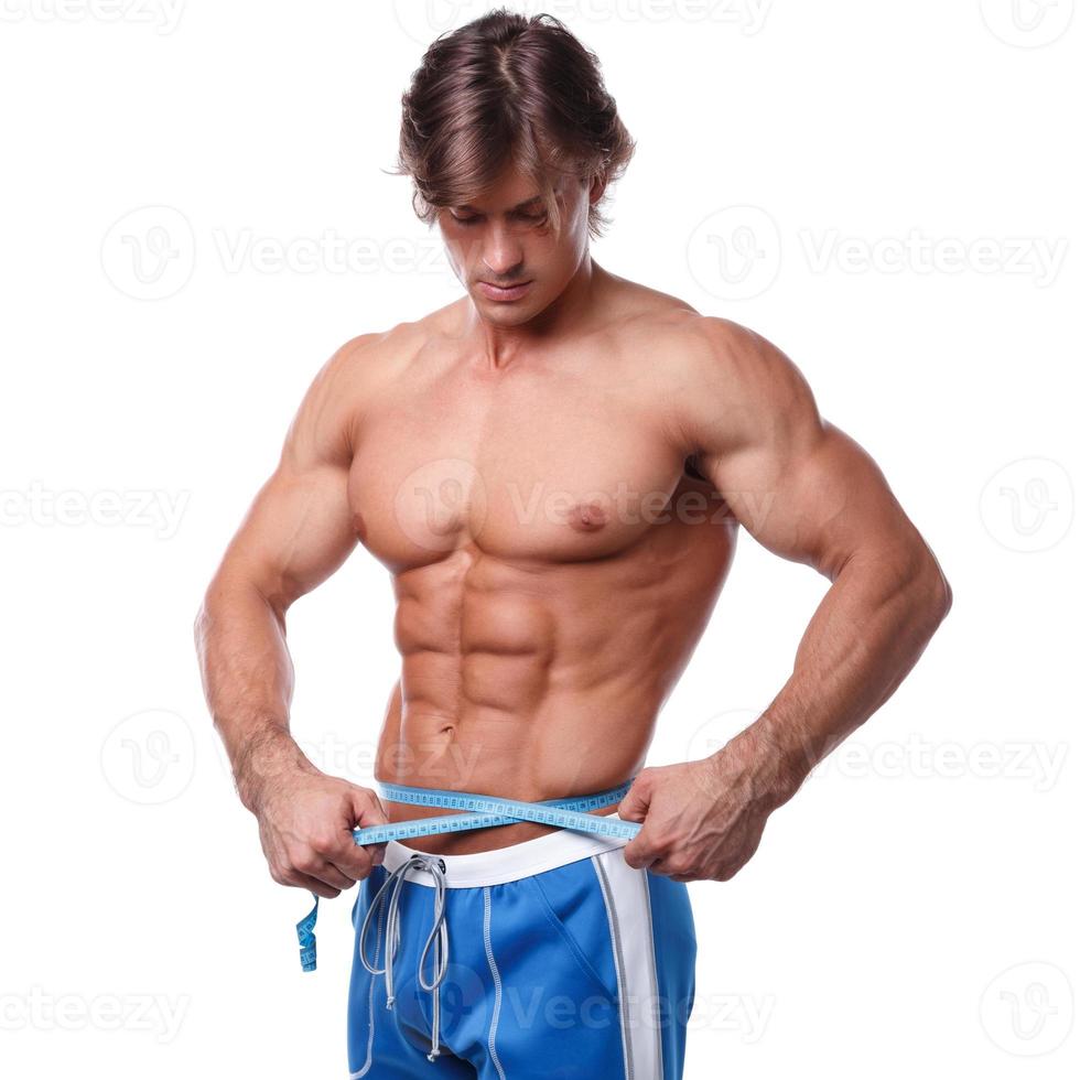 fisiculturista medindo sua cintura sobre fundo branco foto