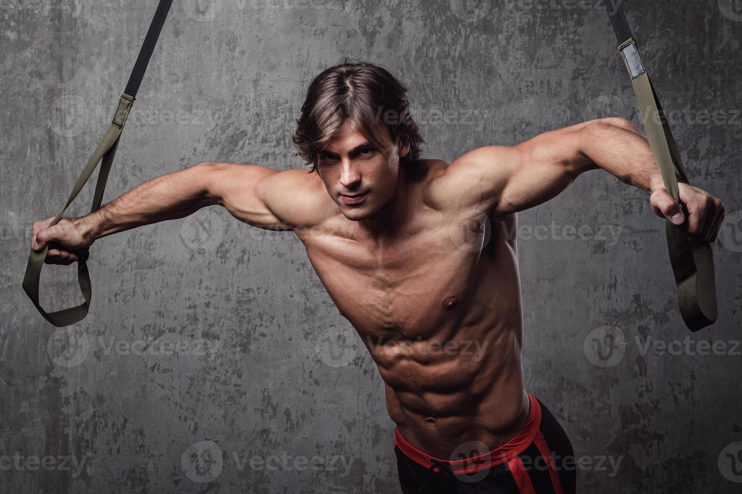 homem musculoso durante treino com cintas de suspensão foto